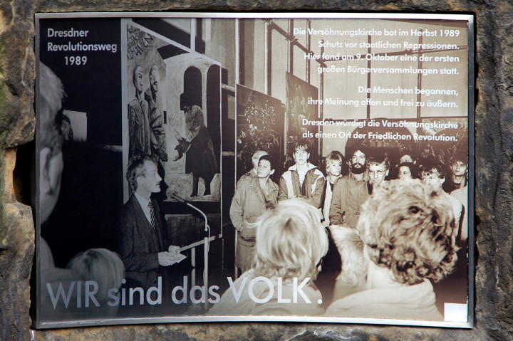 Diese fotodokumentarische Erinnerungstafel an der Außenmauer des Gemeindezentrums Versöhnungskirche zeigt eine Vernissage von 1988 (am Mikrofon Pfarrer Andreas Horn). Foto: Stefan Behr